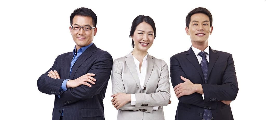 three asian people, one woman in the middle, all in professional suit